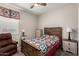 Cozy bedroom with wooden bed frame, quilt bedding, and a comfortable armchair at 14640 W Dahlia Dr, Surprise, AZ 85379