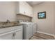 Well-equipped laundry room with granite countertops, white cabinets, and modern appliances at 14640 W Dahlia Dr, Surprise, AZ 85379