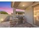 Outdoor kitchen with stone facade, built-in grill, and counter space, adjacent to sliding glass door at 14640 W Dahlia Dr, Surprise, AZ 85379