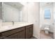 Bright bathroom featuring a single sink vanity, large mirror and a view into the toilet and shower area at 14739 W El Cortez Pl, Surprise, AZ 85387