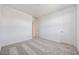 A minimalist bedroom featuring carpeted floors, white walls, and a door to the hallway at 14739 W El Cortez Pl, Surprise, AZ 85387