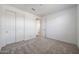 Bedroom with neutral carpet and baseboards, white walls, a walk-in closet, and a view into the hallway at 14739 W El Cortez Pl, Surprise, AZ 85387