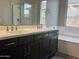 Bathroom boasts dual sinks with chrome faucets, dark cabinets, and a separate soaking tub at 15911 W Montana De Oro Dr, Surprise, AZ 85387