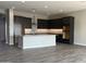 Open-concept kitchen featuring dark cabinets, a center island, and modern appliances at 15911 W Montana De Oro Dr, Surprise, AZ 85387