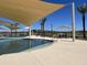 Community pool area featuring sunshades, palm trees, lounge chairs, and a serene pool at 15911 W Montana De Oro Dr, Surprise, AZ 85387