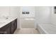 Bright bathroom with soaking tub, shower and double sink vanity leading to a bedroom with a view at 16077 W Remuda Dr, Surprise, AZ 85387