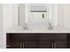 Bright bathroom featuring a double sink vanity with dark cabinets and light counters under a bright window at 16077 W Remuda Dr, Surprise, AZ 85387