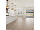 Bright living space with wood-look tile, kitchen island, and sliding glass door leading to the patio at 16081 W Remuda Dr, Surprise, AZ 85387