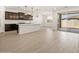 Open layout with wood-look floors, showcasing a modern kitchen and sliding glass door access at 16081 W Remuda Dr, Surprise, AZ 85387