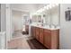 Bright bathroom with double vanity sinks, wooden cabinets, and mirrored sliding door closet at 17696 N 168Th Dr, Surprise, AZ 85374