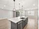 Spacious island kitchen with pendant lighting, stainless steel sink, and gray cabinetry, seamlessly blending into the living area at 17809 W Elm St, Goodyear, AZ 85395