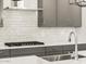 Close-up on the kitchen's stainless steel appliances, gray cabinets, and white backsplash, creating a modern culinary space at 17809 W Elm St, Goodyear, AZ 85395