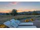 Scenic backyard featuring chaise lounges with mountain views at sunset, surrounded by desert landscaping and flowers at 18332 E Spring Valley Ct, Rio Verde, AZ 85263