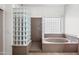 Bathroom featuring a glass block shower and bathtub with neutral tile at 19245 W Pasadena Ave, Litchfield Park, AZ 85340