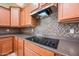 Close up of the kitchen's stovetop with modern appliances and tiled backsplash at 19245 W Pasadena Ave, Litchfield Park, AZ 85340