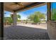 View of covered patio with fan, stone pavers, and manicured landscaping at 301 S 225Th Ave, Buckeye, AZ 85326
