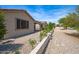 Landscaped side yard with a retaining wall, decorative stone, and a covered patio at 301 S 225Th Ave, Buckeye, AZ 85326