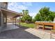Covered patio and landscaped backyard with planters, mature trees, and blue skies overhead at 332 N Cobblestone St, Gilbert, AZ 85234