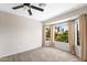 This bedroom has a ceiling fan, carpeted floors, and a window with curtains overlooking trees at 332 N Cobblestone St, Gilbert, AZ 85234