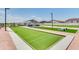 A community bocce ball court with tables, grills and other amenities under a blue sky at 36570 W Maddaloni Ave, Maricopa, AZ 85138