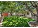 Spacious backyard featuring lush artificial grass, mature trees, covered patio, and convenient side yard access at 645 S 54Th St, Mesa, AZ 85206