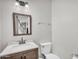 A compact bathroom with a framed mirror over a sink, a toilet, and a glimpse of a staircase in the mirror at 645 S 54Th St, Mesa, AZ 85206