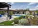 Beautiful backyard featuring a pool, covered patio, colorful landscaping, and lush green grass at 8821 E Havasupai Dr, Scottsdale, AZ 85255