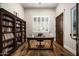 Well-lit home office with wood floors features custom bookshelf and bright natural light from large window at 8821 E Havasupai Dr, Scottsdale, AZ 85255