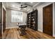Well-lit home office boasts custom bookshelf with ladder, wood floors, and bright natural light at 8821 E Havasupai Dr, Scottsdale, AZ 85255