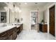 Bright main bathroom with dual sink vanity, elegant chandelier lighting, and backyard access at 8821 E Havasupai Dr, Scottsdale, AZ 85255