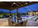 Relaxing outdoor area featuring a covered dining space with a clear view of the pool at twilight at 8821 E Havasupai Dr, Scottsdale, AZ 85255