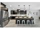 Stylish kitchen featuring dark cabinetry, a spacious island with seating, and stainless-steel appliances at 13553 N 141St Ln, Surprise, AZ 85379