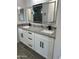 Elegant bathroom featuring dual sinks, granite countertops, white cabinets with dark pulls, and gray wood-look tile floors at 14861 S Capistrano Rd, Arizona City, AZ 85123