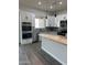 Bright kitchen features white cabinets, granite counters, stainless appliances, tile backsplash, and gray wood-look tile floors at 14861 S Capistrano Rd, Arizona City, AZ 85123