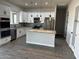 Bright kitchen features an island, granite countertops, white cabinets, stainless appliances, and gray wood-look tile floors at 14861 S Capistrano Rd, Arizona City, AZ 85123
