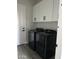 Laundry room features black washer and dryer, gray tile floors, and white upper cabinets at 14861 S Capistrano Rd, Arizona City, AZ 85123