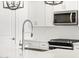Close-up of a modern kitchen featuring white cabinets, quartz counters, stainless appliances, and designer faucet at 16071 W Remuda Dr, Surprise, AZ 85387