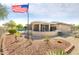 Backyard with desert landscaping, a screened-in patio, an American flag, and a sparkling blue pool at 16384 W Salado Creek Dr, Surprise, AZ 85387