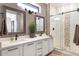 Modern bathroom with double sinks, decorative mirrors, and a stylish glass-enclosed shower at 16384 W Salado Creek Dr, Surprise, AZ 85387