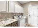 Functional laundry room with ample cabinet space, a sink, and modern washer and dryer at 16384 W Salado Creek Dr, Surprise, AZ 85387