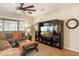 Cozy living room with stylish decor, comfortable seating, ceiling fan, and large entertainment center at 16384 W Salado Creek Dr, Surprise, AZ 85387