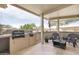 Outdoor kitchen with built-in grill and seating under a covered patio, perfect for entertaining at 16384 W Salado Creek Dr, Surprise, AZ 85387