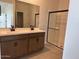 Bright bathroom with double sink vanity, wood cabinets and glass enclosed walk-in shower at 17043 W Fetlock Trl, Surprise, AZ 85387