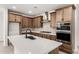 Close-up of a modern kitchen featuring a kitchen island, stainless steel appliances, and wood cabinets at 17043 W Fetlock Trl, Surprise, AZ 85387
