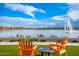 Enjoy the serene lake view from the comfort of two chairs with clear blue skies and landscaping at 17244 W West Wind Dr, Surprise, AZ 85387