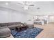 Open-concept living room with a gray sofa, blue rug, and modern lighting that connects to the kitchen at 17244 W West Wind Dr, Surprise, AZ 85387