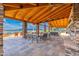 Spacious outdoor lounge with stone pillars, wood ceiling, comfortable seating, and a tranquil view of the lake at 17244 W West Wind Dr, Surprise, AZ 85387