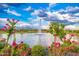 Scenic pond with a central fountain, surrounded by lush greenery and vibrant pink flowers under a bright sky at 17244 W West Wind Dr, Surprise, AZ 85387
