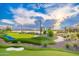 Putting green with artificial stream, white sand trap, stone-lined walkway, and lush landscaping for an engaging outdoor space at 17244 W West Wind Dr, Surprise, AZ 85387