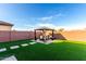 Backyard featuring a patio set beneath a gazebo-like structure, surrounded by synthetic grass at 25627 N 163Rd Dr, Surprise, AZ 85387
